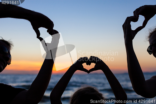 Image of Silhouette of happy family who playing on the beach at the sunse