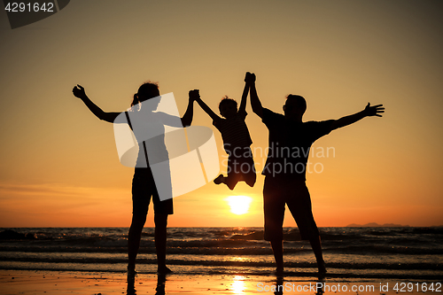 Image of Silhouette of happy family who playing on the beach at the sunse