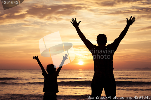 Image of Father and son playing on the beach at the sunset time.