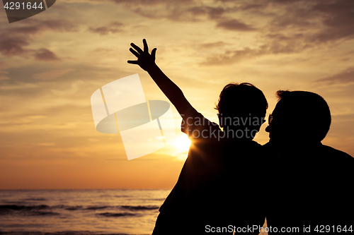 Image of Father and son playing on the beach at the sunset time.