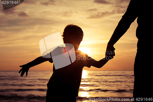 Image of Father and son playing on the beach at the sunset time.