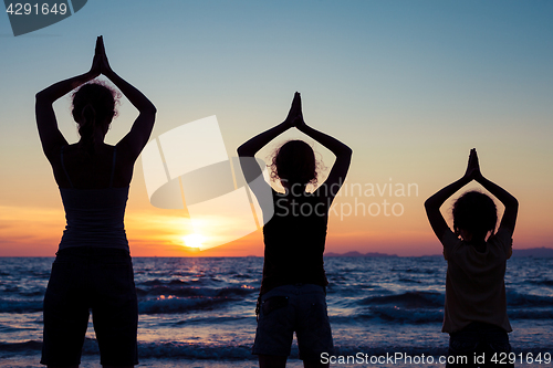 Image of Mother and daughters playing on the beach at the sunset time.