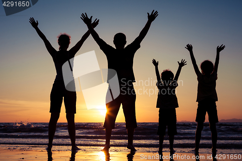 Image of Silhouette of happy family who playing on the beach at the sunse