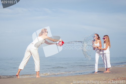 Image of Mother and daughters  playing with umbrella on the beach at the 