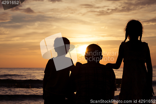 Image of Father and children playing on the beach at the sunset time.