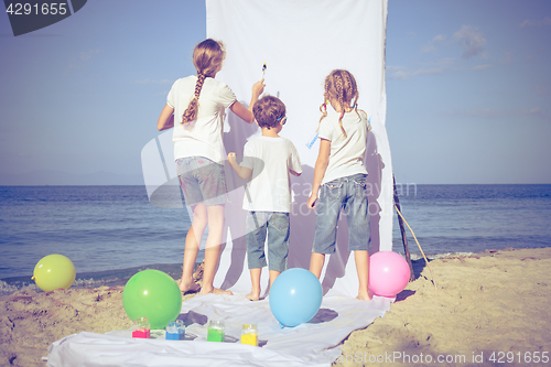 Image of Two sisters and brother playing on the beach at the day time.