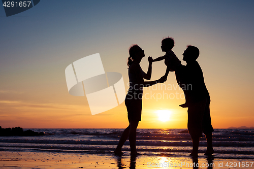 Image of Silhouette of happy family who playing on the beach at the sunse
