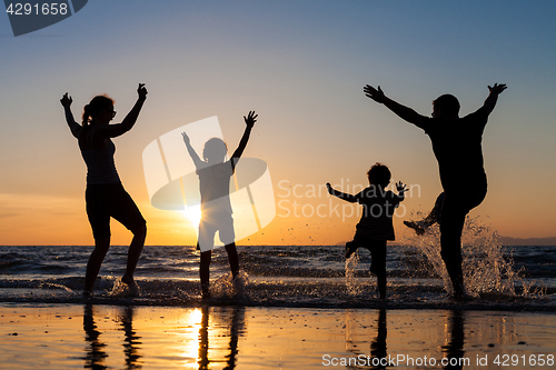 Image of Silhouette of happy family who playing on the beach at the sunse