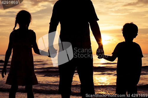 Image of Father and children playing on the beach at the sunset time.