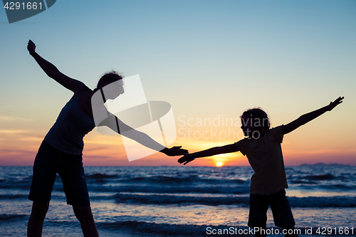 Image of Mother and daughter playing on the beach at the sunset time.