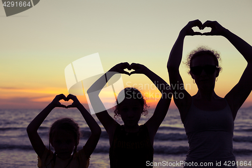 Image of Mother and daughters playing on the beach at the sunset time.