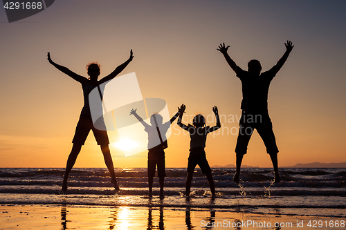 Image of Silhouette of happy family who playing on the beach at the sunse