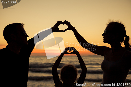 Image of Silhouette of happy family who playing on the beach at the sunse