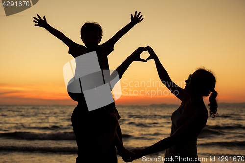 Image of Silhouette of happy family who playing on the beach at the sunse