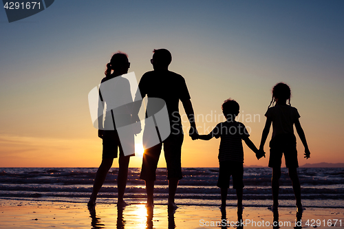 Image of Silhouette of happy family who playing on the beach at the sunse