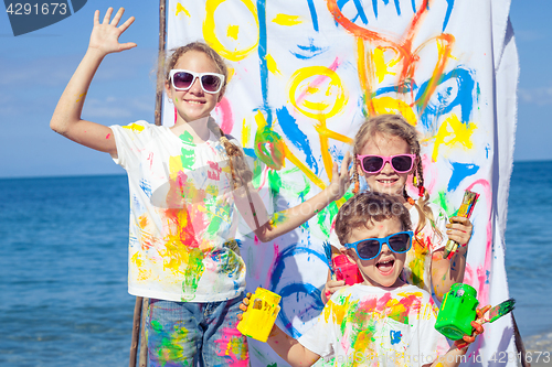 Image of Two sisters and brother playing on the beach at the day time. 