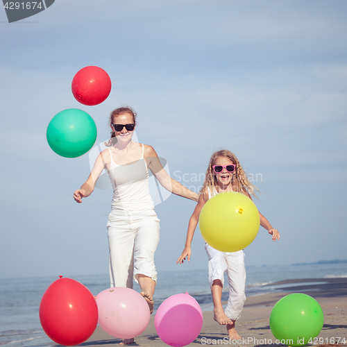 Image of Mother and daughter playing with balloons on the beach at the da