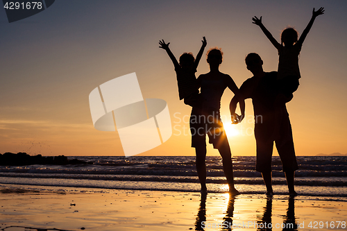 Image of Silhouette of happy family who standing on the beach at the suns