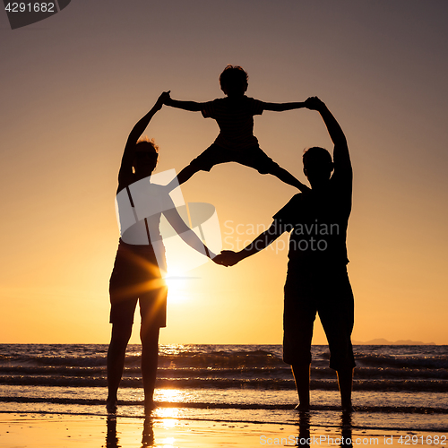 Image of Silhouette of happy family who playing on the beach at the sunse