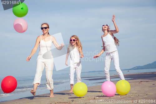 Image of Mother and daughters  playing with balloons on the beach at the 