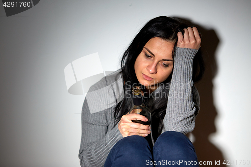 Image of unhappy drunk crying woman with bottle of alcohol