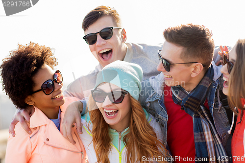 Image of happy teenage friends in shades laughing outdoors