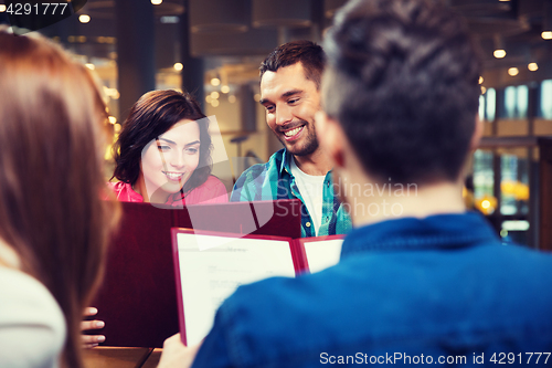 Image of smiling couple with friends and menu at restaurant