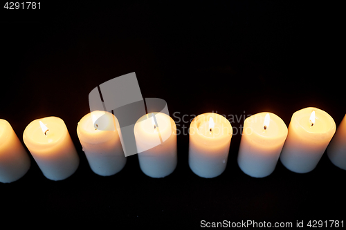 Image of candles burning in darkness over black background