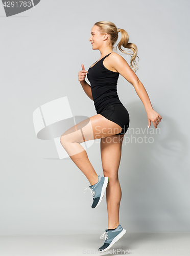 Image of young woman in black sportswear jumping