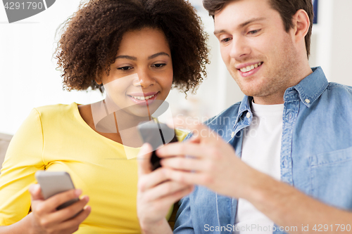 Image of happy couple with smartphones at home