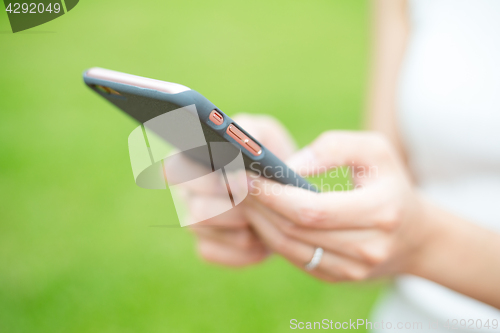 Image of Woman hold a mobile phone over green plant background