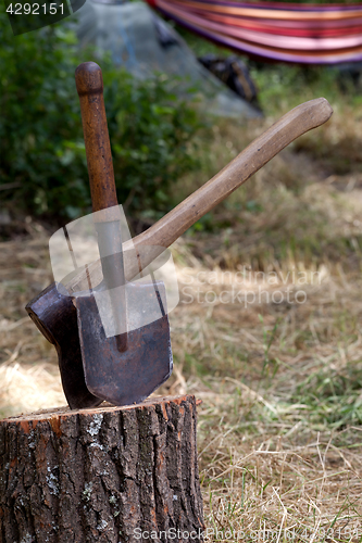 Image of Stump with axe and shovel at camping