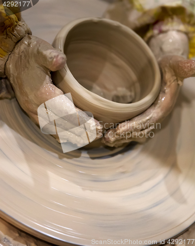 Image of Young girl in process of making clay bowl on pottery wheel