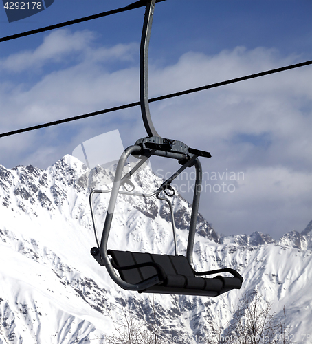 Image of Chair lift in snowy mountains at nice sun day