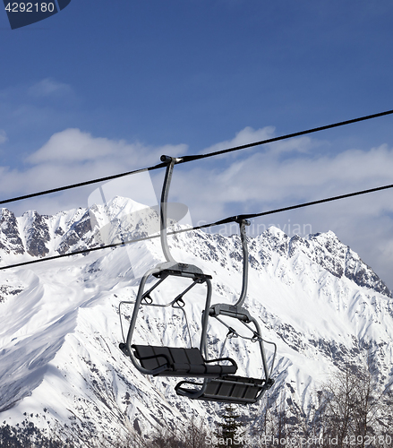 Image of Chair lift in snowy mountains at nice sun day