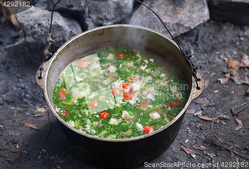 Image of Freshly cooked hot soup in sooty cauldron at camping
