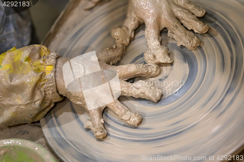 Image of Hands of young girl in clay on pottery wheel