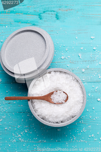 Image of Sea salt in an stone bowl with small wooden spoon on a blue wooden table