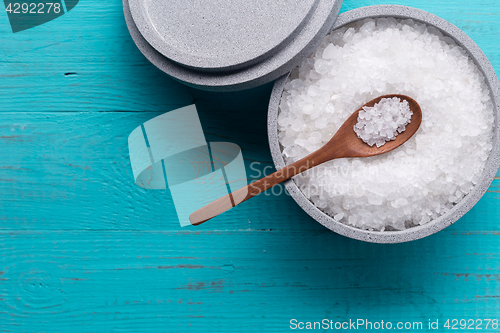 Image of Sea salt in an stone bowl with small wooden spoon on a blue wooden table