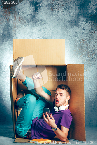 Image of Introvert concept. Man sitting inside box and working with phone