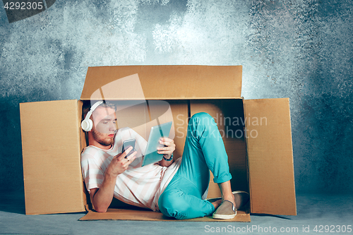 Image of Introvert concept. Man sitting inside box and working with phone