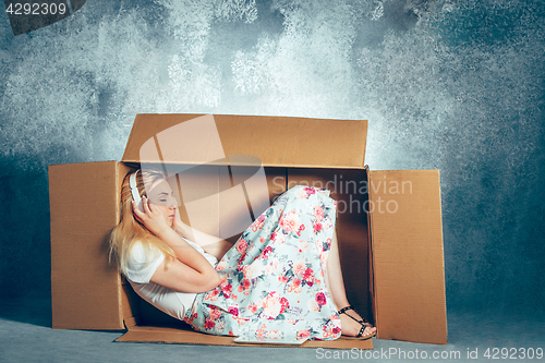 Image of Introvert concept. Woman sitting inside box and working with laptop