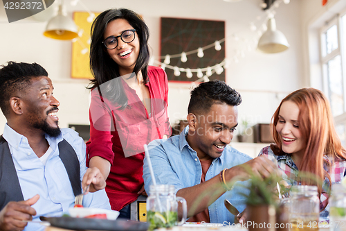 Image of happy friends eating at restaurant