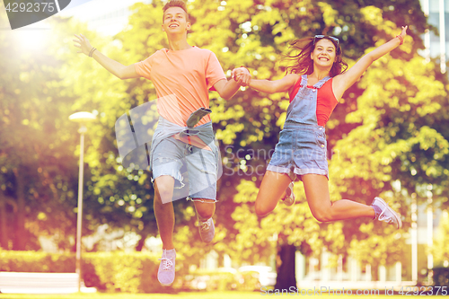 Image of happy teenage couple jumping at summer park