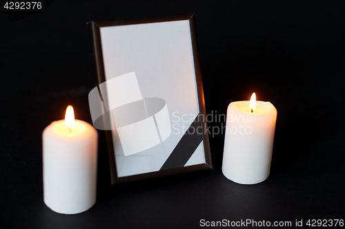 Image of black ribbon on photo frame and candles at funeral