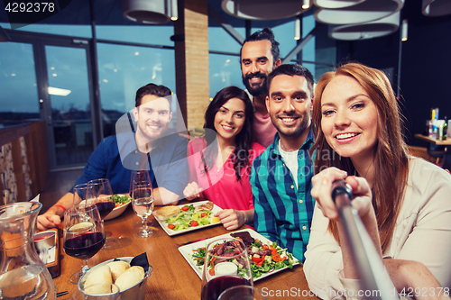 Image of friends picturing by selfie stick at restaurant