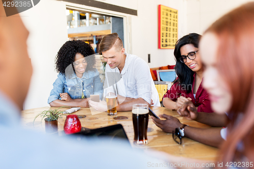 Image of happy friends with smartphone drinking beer at bar