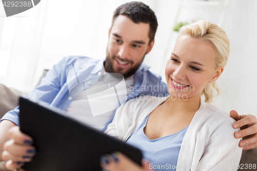 Image of smiling happy couple with tablet pc at home