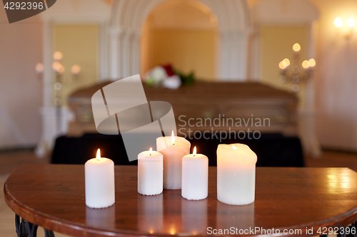 Image of burning candles and coffin in church at funeral