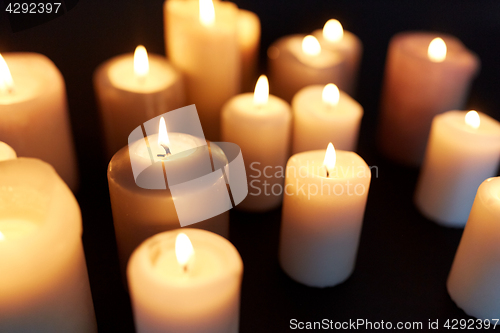 Image of candles burning in darkness over black background